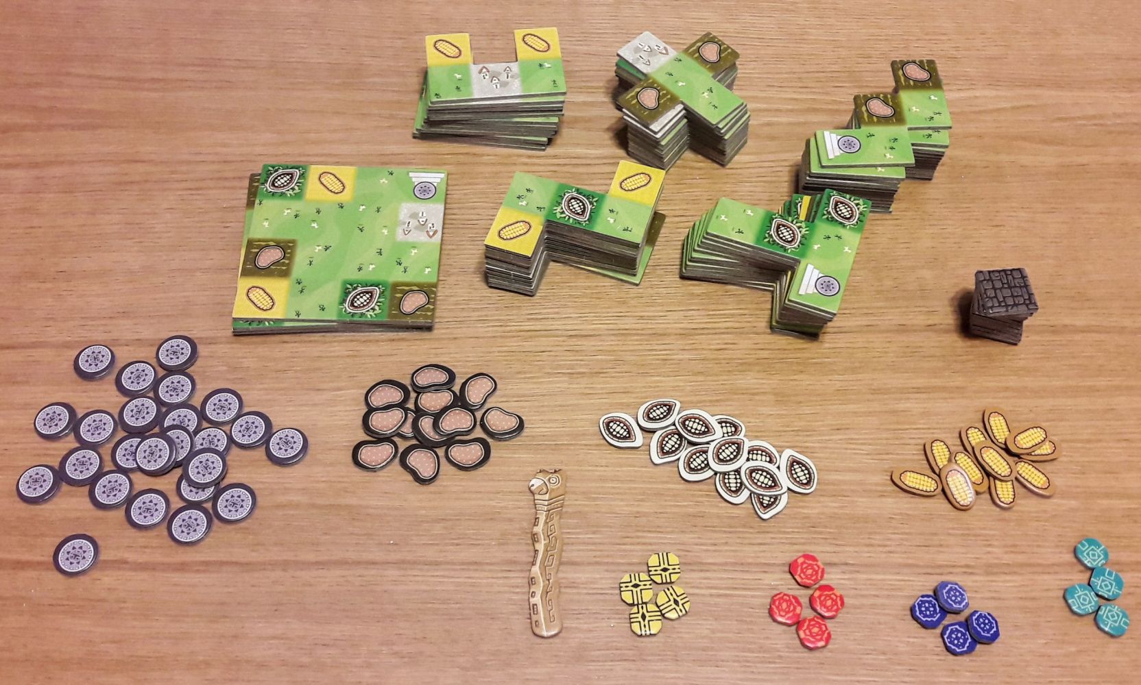 Une fois dépunché, on a plein de tuiles de 5 formes différentes et des jetons ressources, des pièces, et des jetons joueurs.