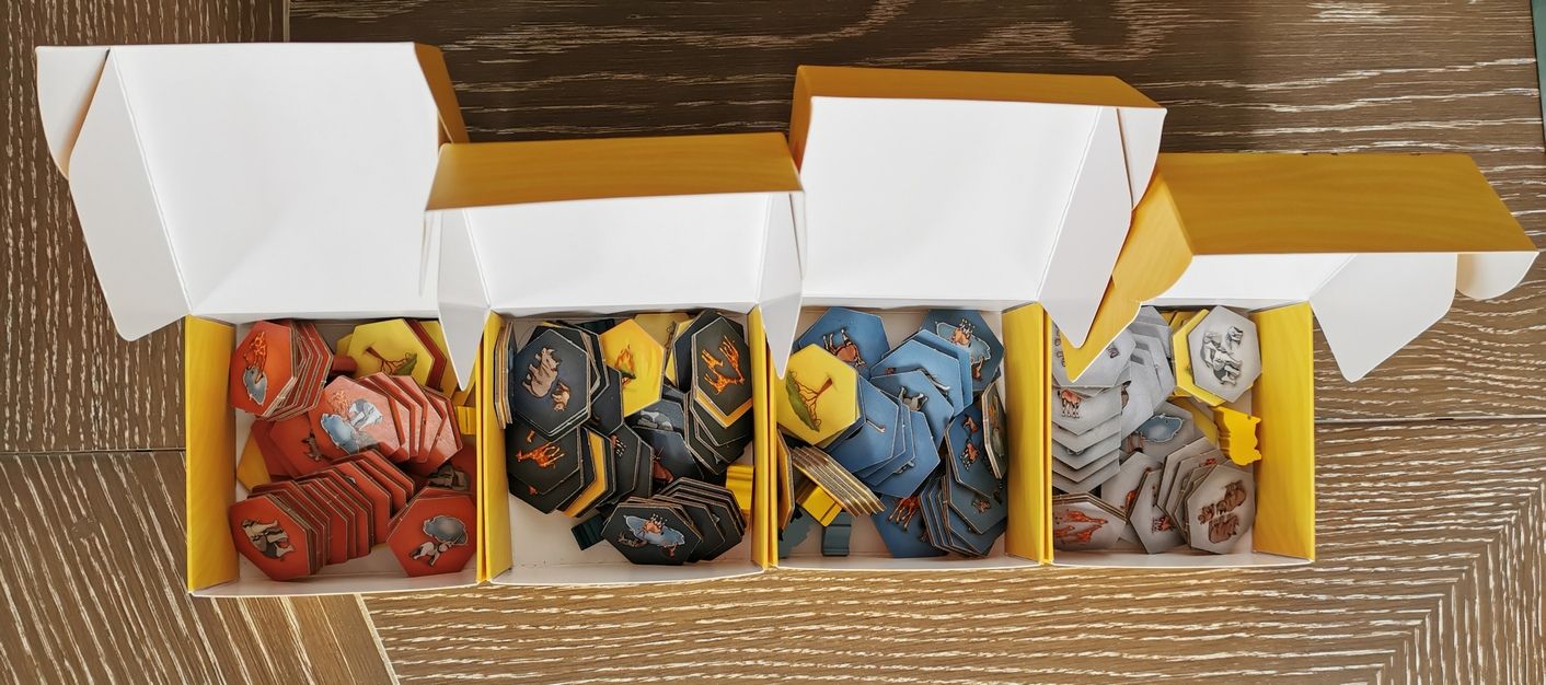 les 4 petites boîtes ouvertes, meeples et tuiles à profusion .