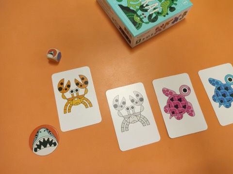 Si le dé Attaque tombe sur la face Requin, le joueur place la carte la plus proche de sa tuile Requin-tigre dans la défausse face visible. Si le dé tombe sur la face Algues, il ne se passe rien.