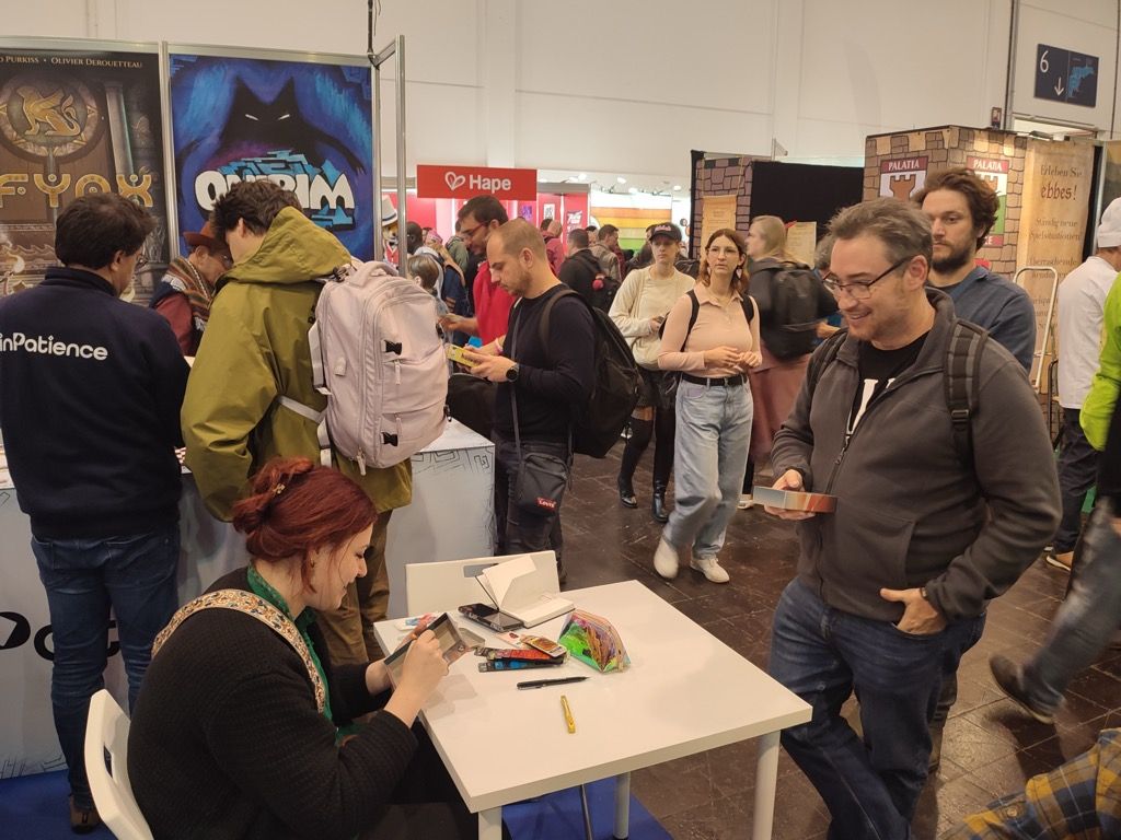 Jean-rémy tente un grand coup auprès de Christine Alcouffe : se faire dédicacer sa boite de R.A.V.E.L. avec un dessin d'Alice : de l'autre côté du miroir (jeu acheté la veille).