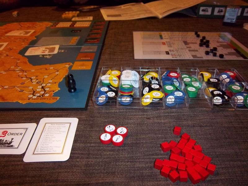 Une partie du matériel : pas de cubes en bois pour les marchandises, mais des jetons de couleurs posés sur des cartes (mines ou exploitations de bois). Les cubes servent à marquer la propriété. 